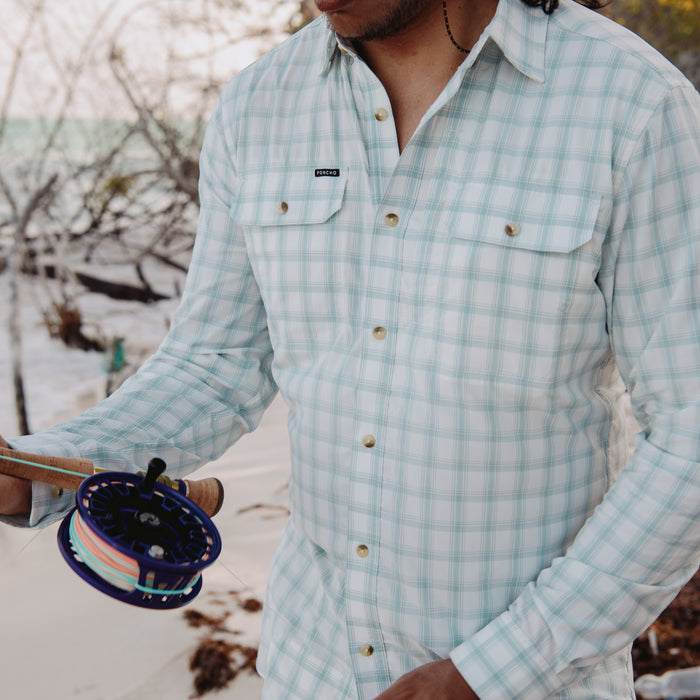 man holding fly rod on beach in the 12 weight shirt