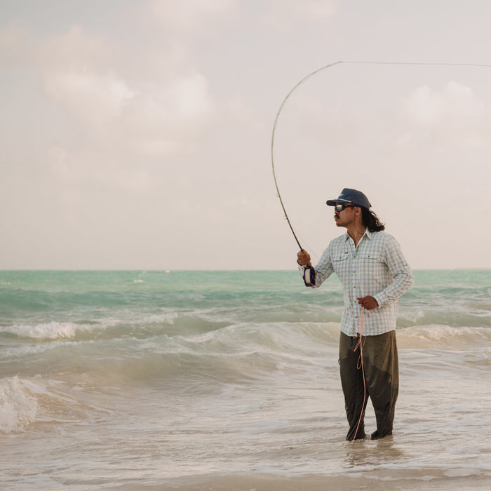 man casting fly rod in surf in 12 weight shirt