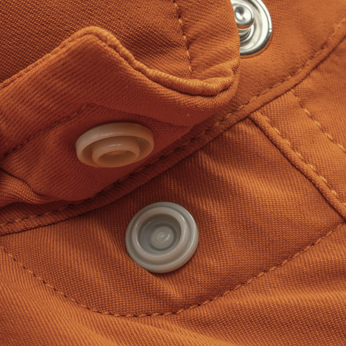 Close-up of rust-colored fabric with snap buttons detail from The 2005 shirt, showcasing durable stitching and hardware.