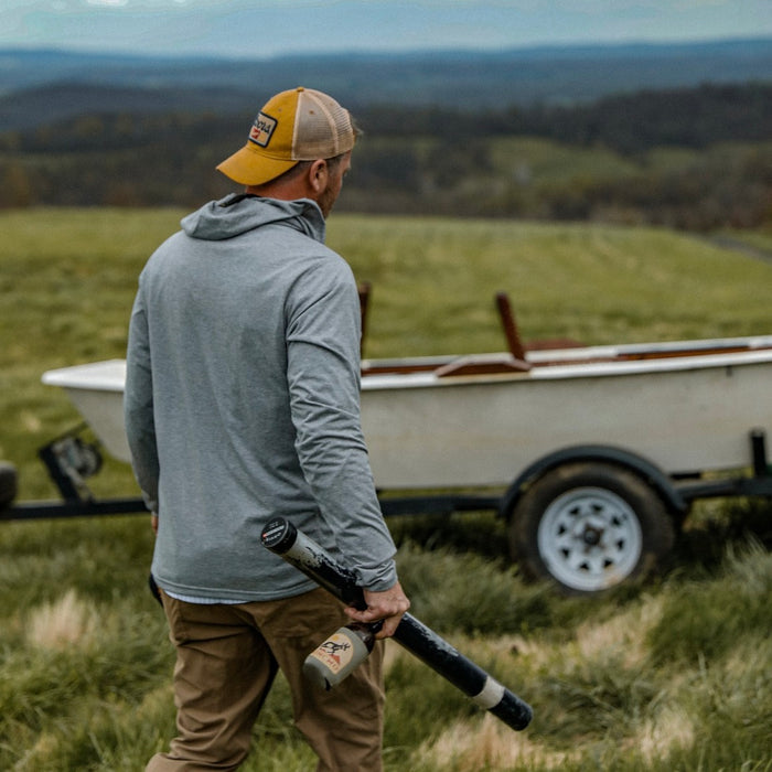 can holding beverage and fishing rod case  wearing grey hoodie