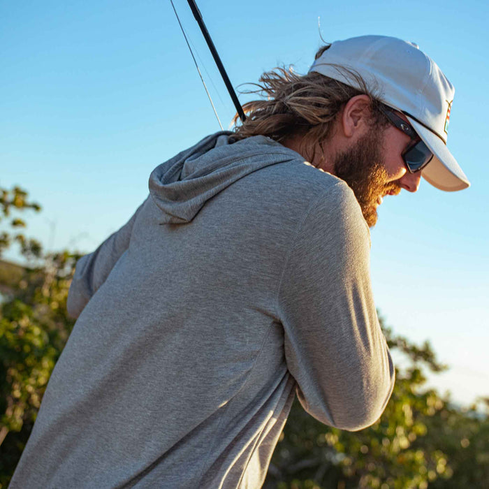 man holding fishing rd wearing grey hoodie