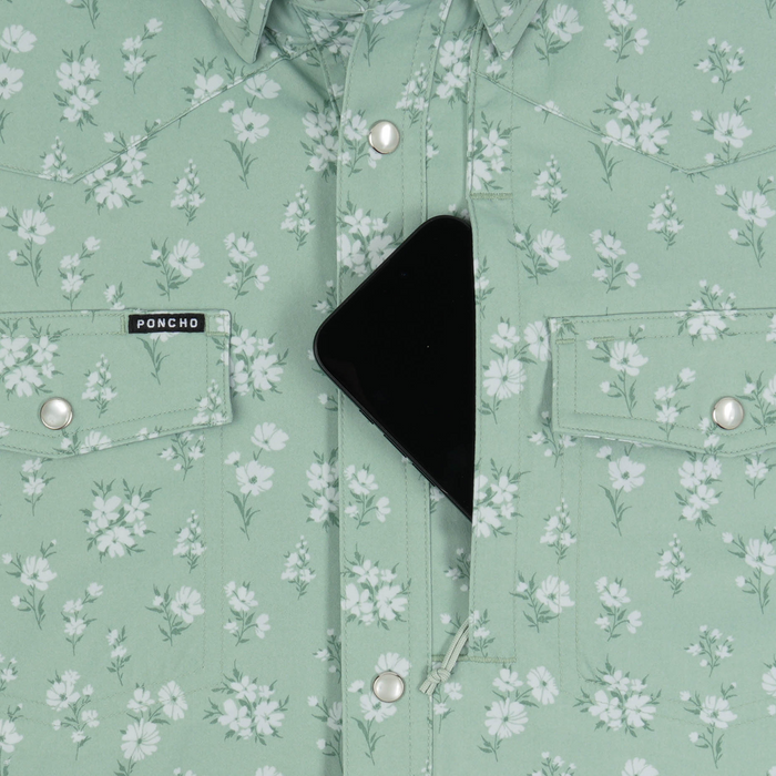 Close-up of a mint green floral shirt by Poncho Outdoors with buttoned pockets and a phone partially tucked inside, The Bat Masterson.