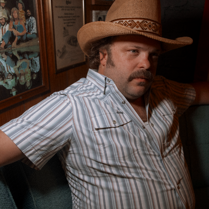 The Big Rig striped shirt worn with a woven cowboy hat in a rustic interior
