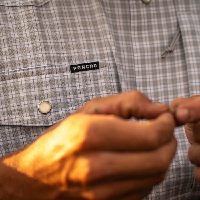 The Bighorn plaid shirt with a Poncho label as hands fasten a button