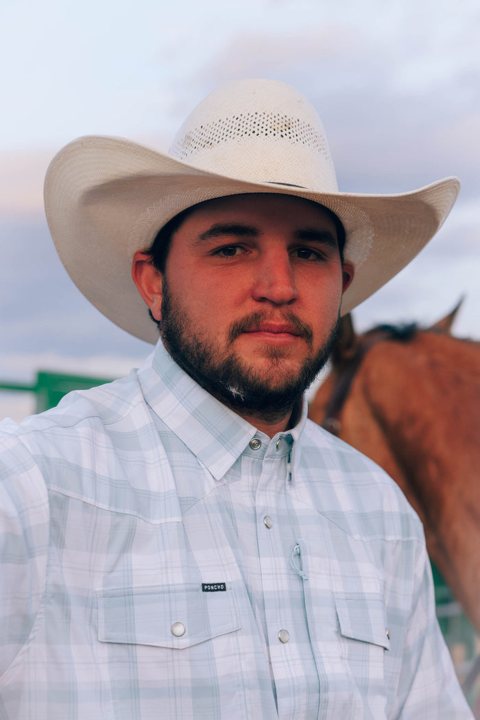 Man wearing The Billings outdoor shirt and cowboy hat standing near a horse