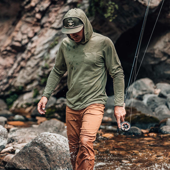 guy wearing moss green hoodie walking in water