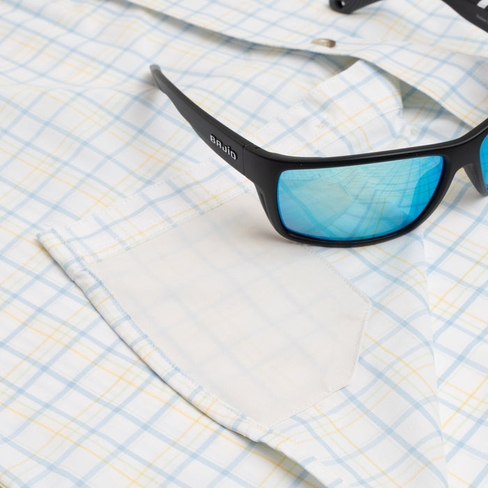 sunglasses laying on blue and yellow button down shirt
