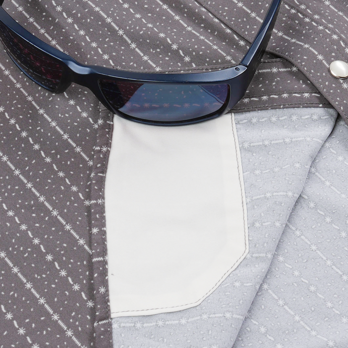 Close-up of a patterned shirt pocket detail with sunglasses resting on it, featuring The Camino design.