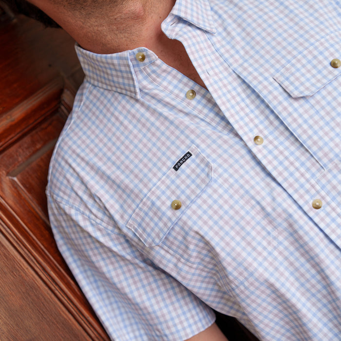 The Channel Cat light blue and white plaid button down shirt worn by a person seated indoors
