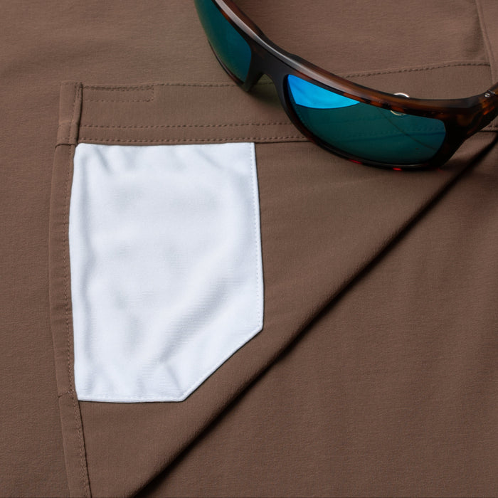Close-up of The Clark outdoor shirt pocket with sunglasses resting on brown fabric