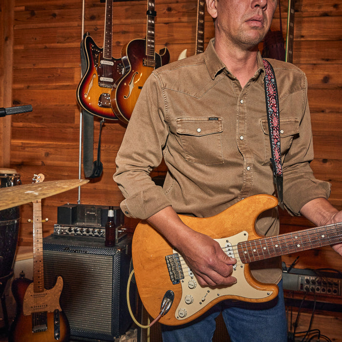 Man playing guitar in brown denim shirt