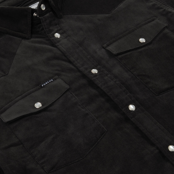 Close-up of a black shirt with snap buttons and flap pockets, showcasing details of The Dusty Burro shirt design.