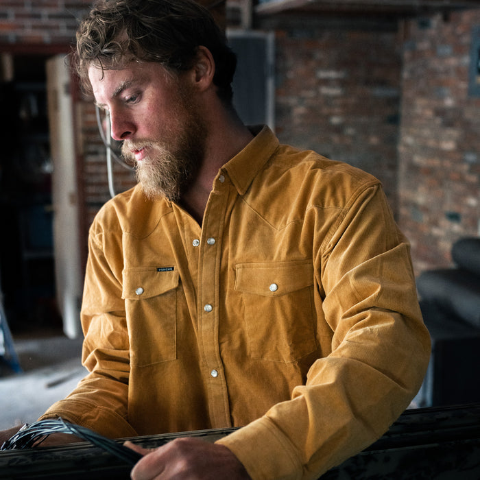 Man holding barbed wire in corduroy shirt