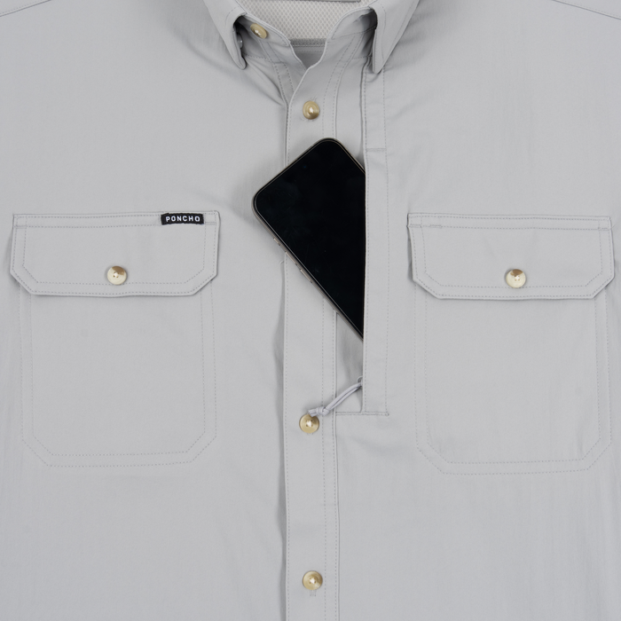 Close-up of The Grey Ghost shirt in light grey with front pockets and a phone partially tucked into the center placket.