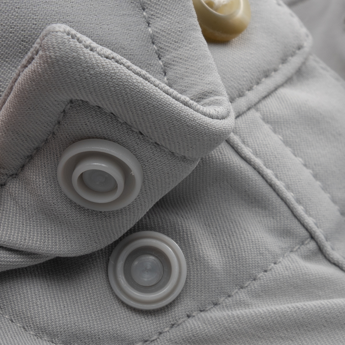 Close-up of grey fabric with detailed stitching and snap buttons on The Grey Ghost shirt