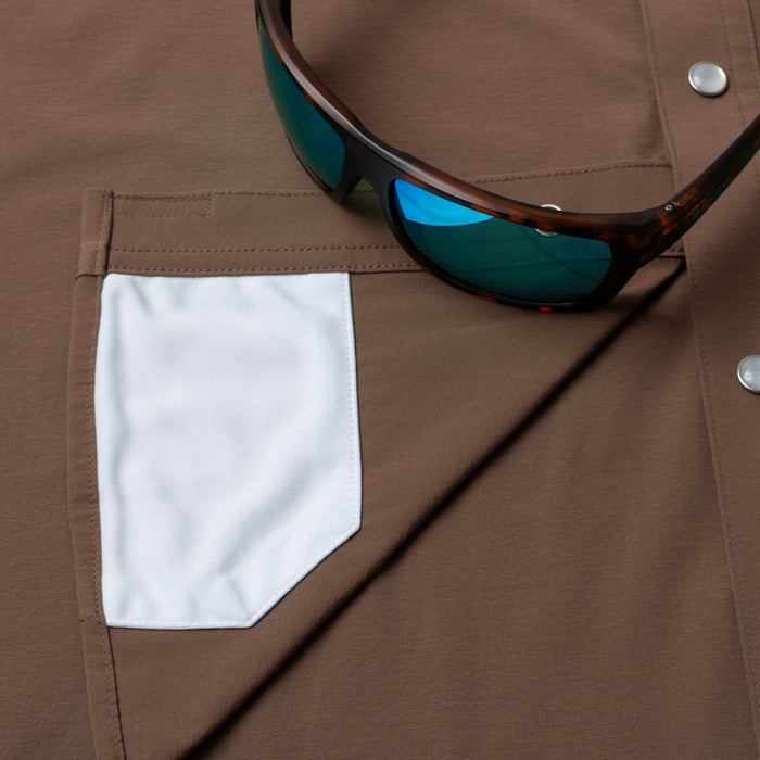 Close-up of brown fabric with white pocket detail and sunglasses on The Lewis outdoor shirt