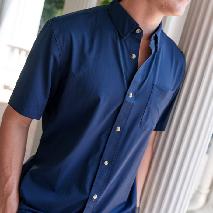 The Listo navy short sleeve shirt with button front and chest pocket, modeled indoors