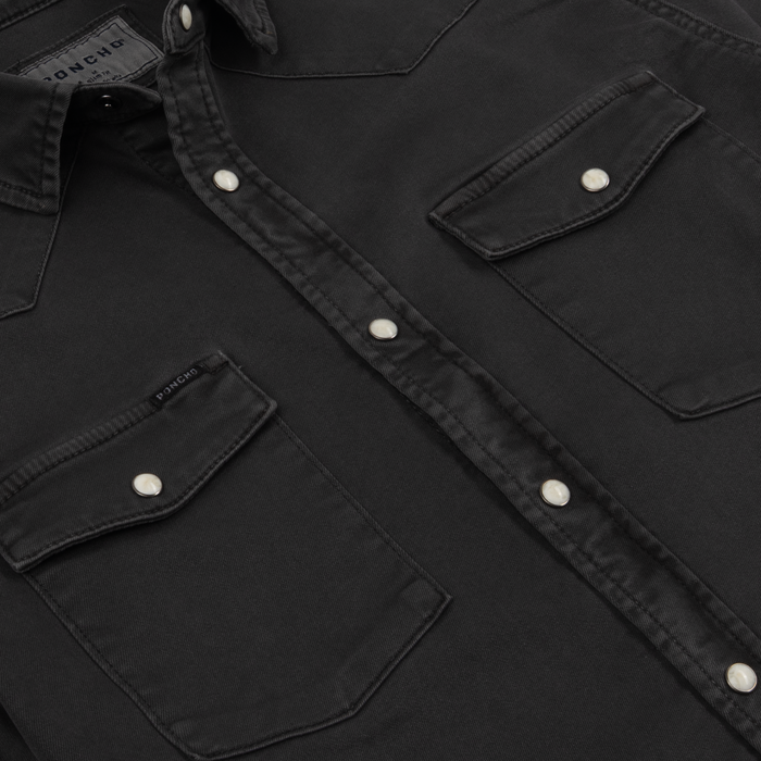 Close-up of The Matamoros shirt in black with pearl snap buttons and double chest pockets.