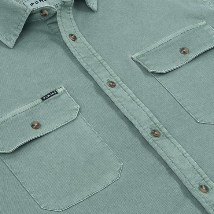 Close-up of light green button-up shirt with flap pockets and brown buttons from The Mentone collection by Poncho Outdoors
