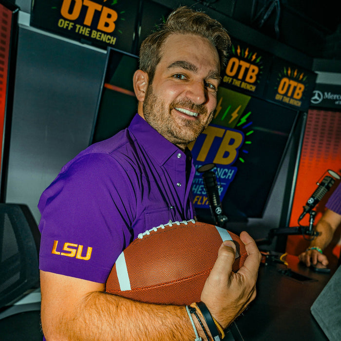 man holding football wearing purple LSU shirt