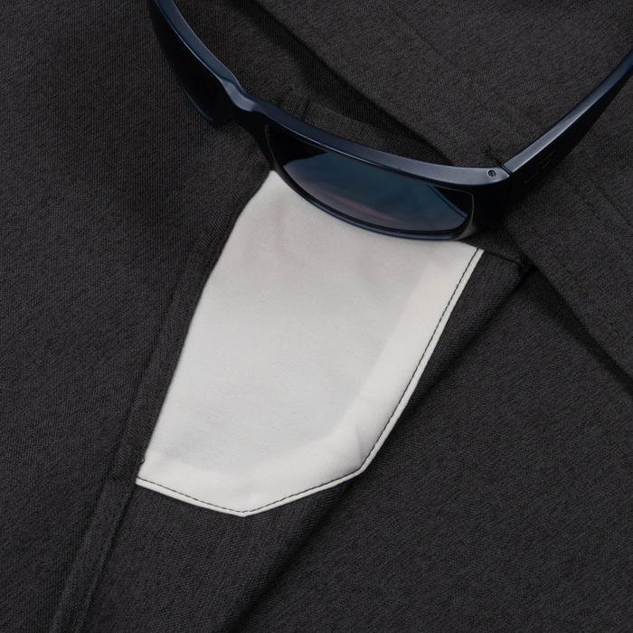 Close-up of dark fabric and a white pocket detail on The Nighthawk shirt with dark sunglasses resting on top.