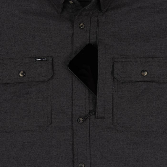 Close-up of The Nighthawk shirt in dark fabric featuring secure chest pockets, one holding a smartphone.