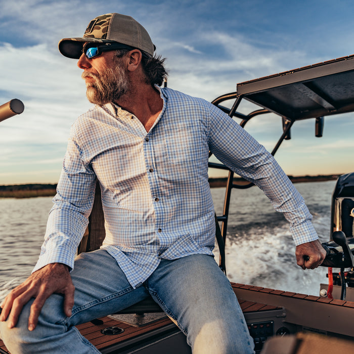 man driving boat in blue plaid long sleeve