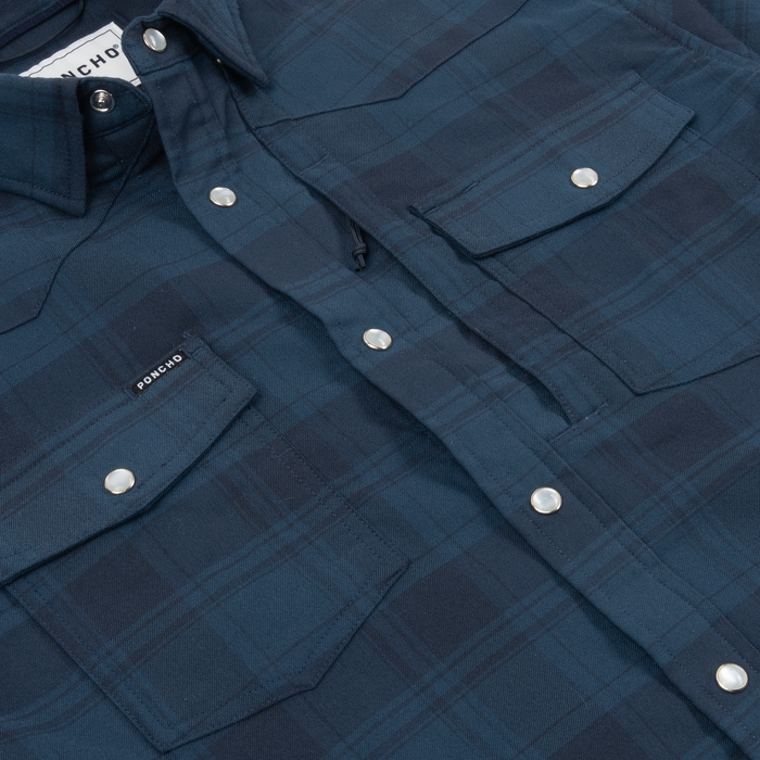 Close-up of a navy plaid shirt with snap buttons and pockets, featuring The Powder River design.