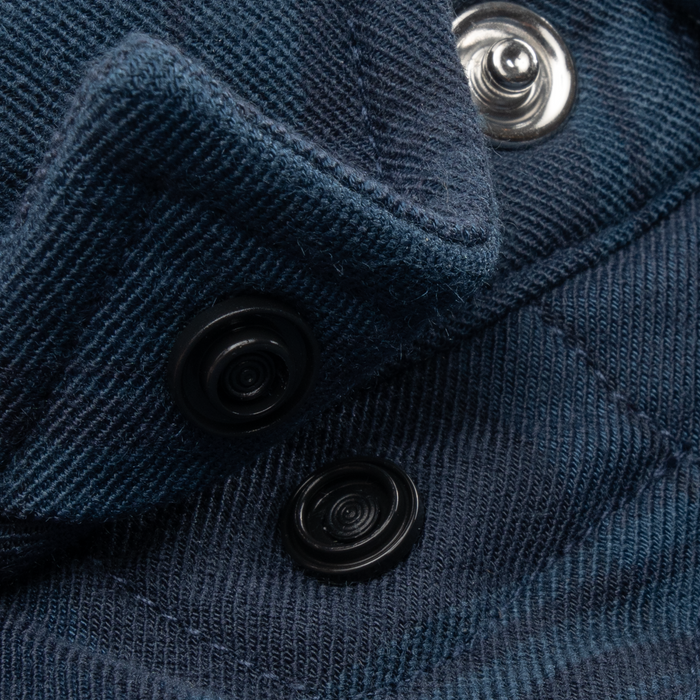 Close-up of dark blue fabric with textured weave and black and silver snap buttons on The Powder River shirt.