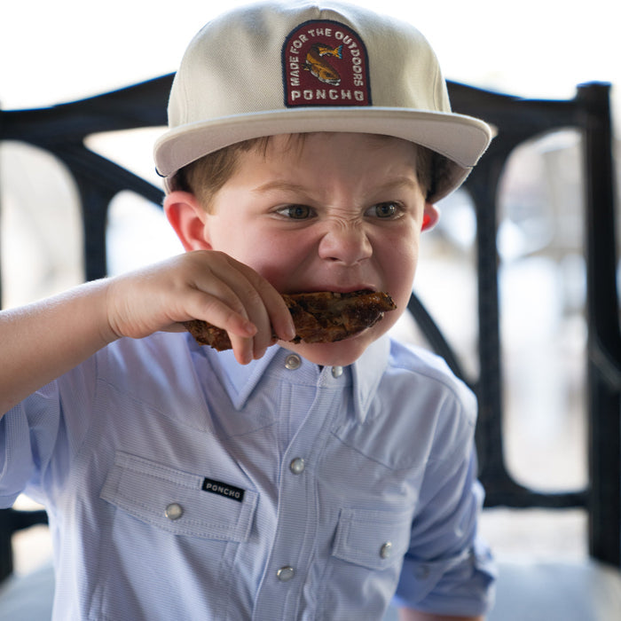 Kid eating chicken in a blue microcheck kid's shirt