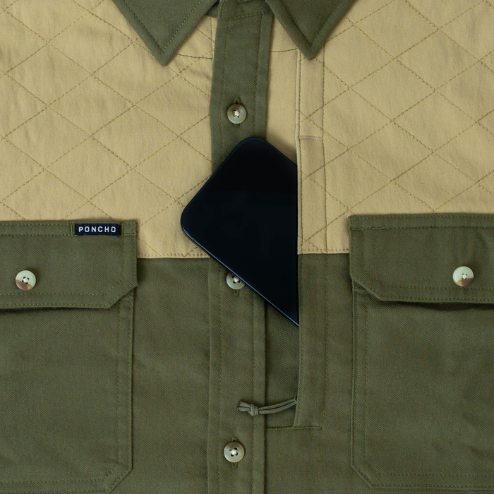 Close-up of The Roosevelt outdoor shirt pocket holding a phone, showing quilted and solid fabric design
