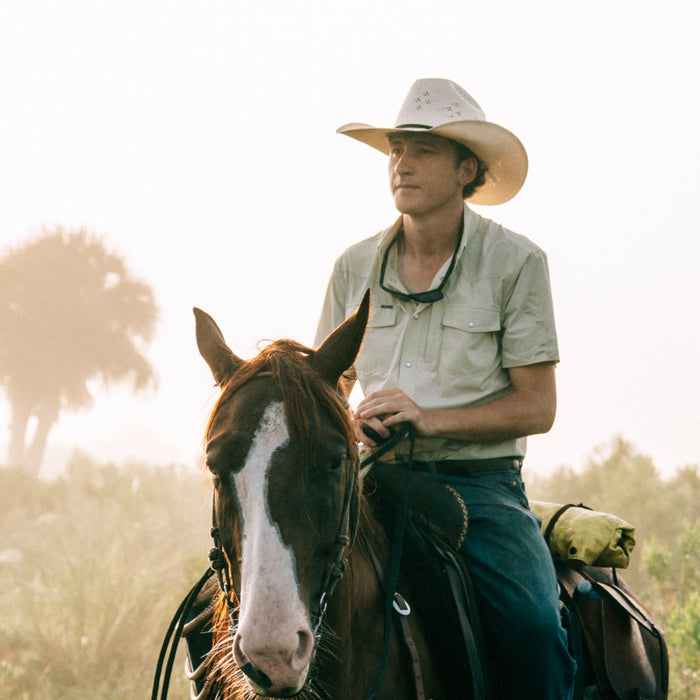 man riding horse wearing tan short sleeve tuff-thread shirt