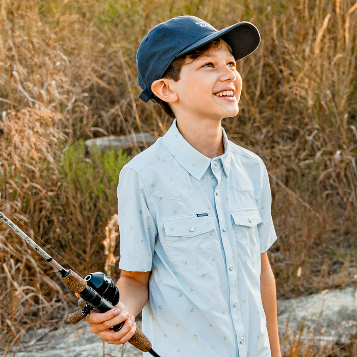 boy holding a fishing pole wearing pearl snap fishing shirt