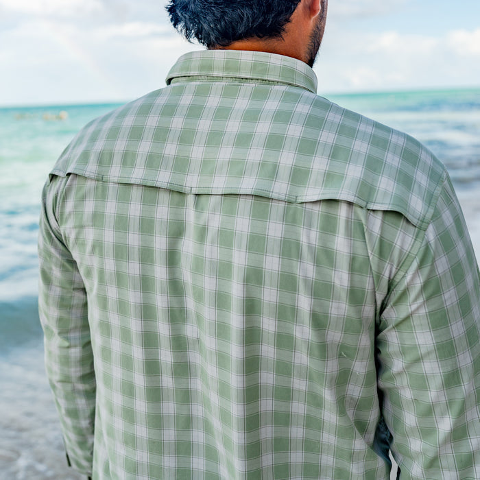 Back view of a man wearing The Sapelo green plaid outdoor shirt near the ocean