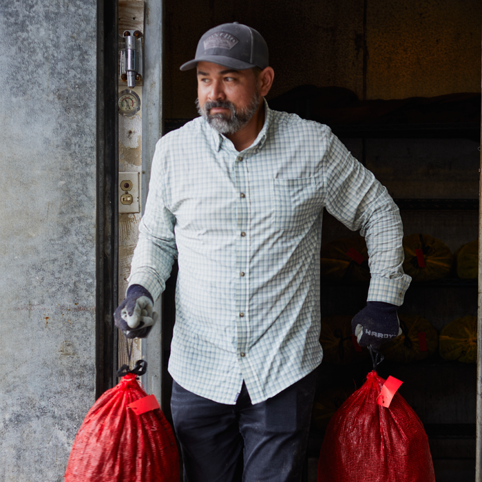 man carrying bags in green plaid button up