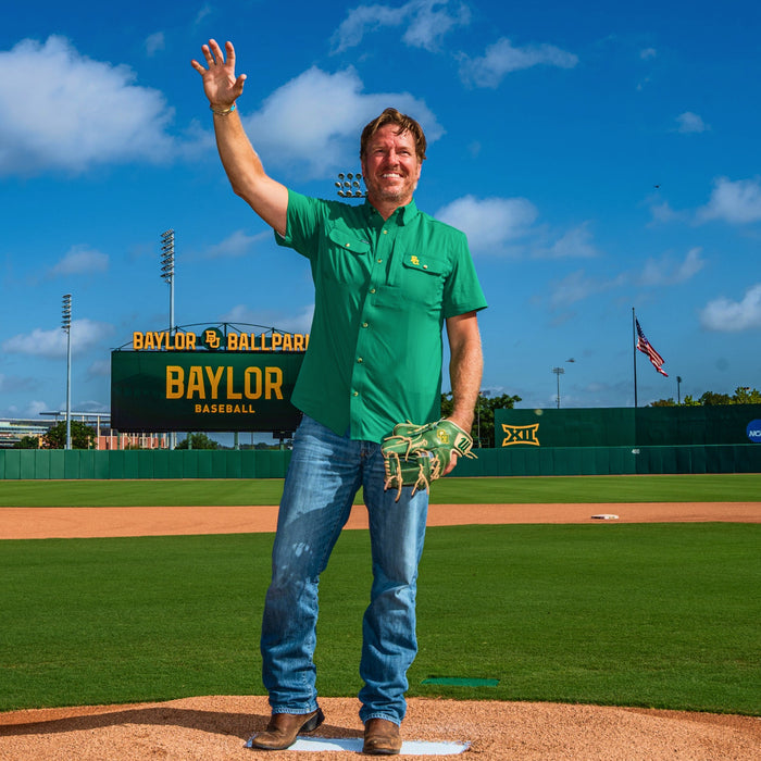man on baseball field wearing green baylor shirt