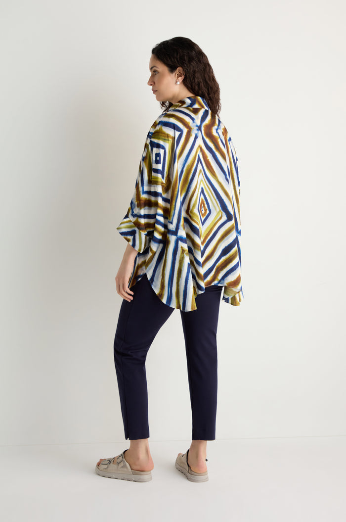 A woman stands sideways wearing the Wavy Lines Print Shirt, dark pants, and beige sandals, set against a plain white background.